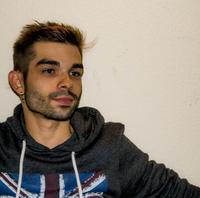 Joven con cabello corto, camiseta gris, y fondo claro, mirando pensativamente.